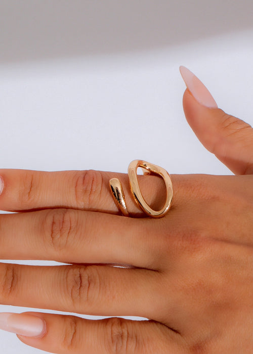 Infinity Loop Ring Gold shining on a woman's finger, reflecting light 