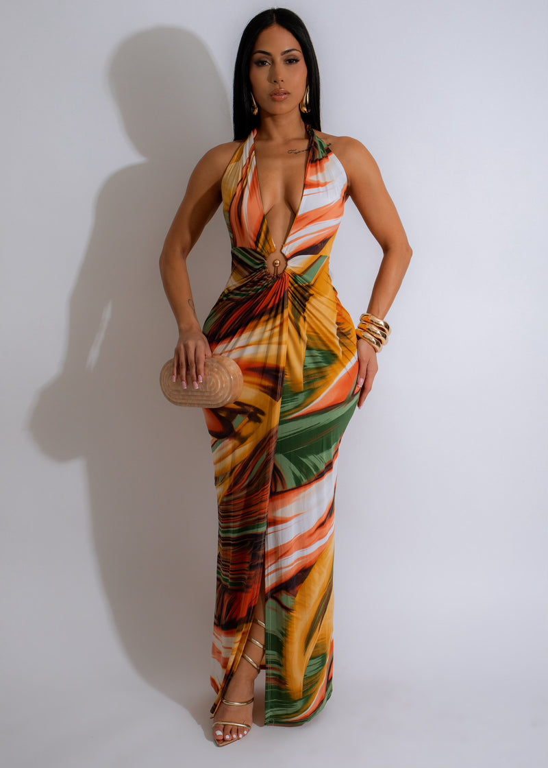 Beautiful woman wearing a flowing Sunset Maxi Dress in bright orange at the beach during sunset, feeling comfortable and elegant