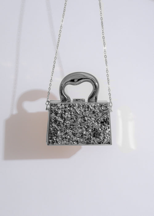  A close-up image of the What I Need Clutch Silver, showcasing its intricate metallic detailing and elegant design