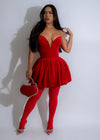 Close-up of a woman wearing a red Buttercup Velvet Mini Dress with a sweetheart neckline and adjustable spaghetti straps, paired with strappy heels and statement earrings