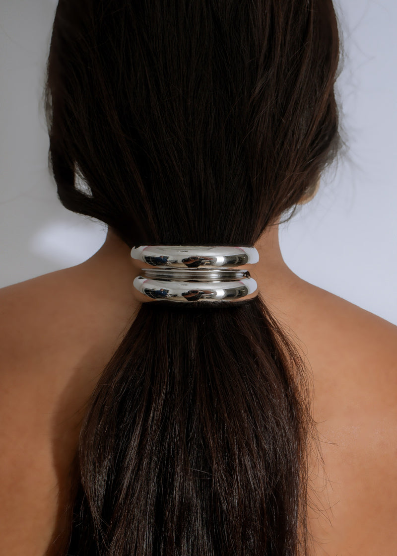 Close up image of Luxe Loop Hair Tie in Silver color on a white background, showing the intricate detail of the metal design 