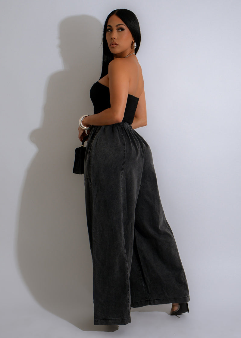 Model wearing black denim jumpsuit with pockets and wide leg design