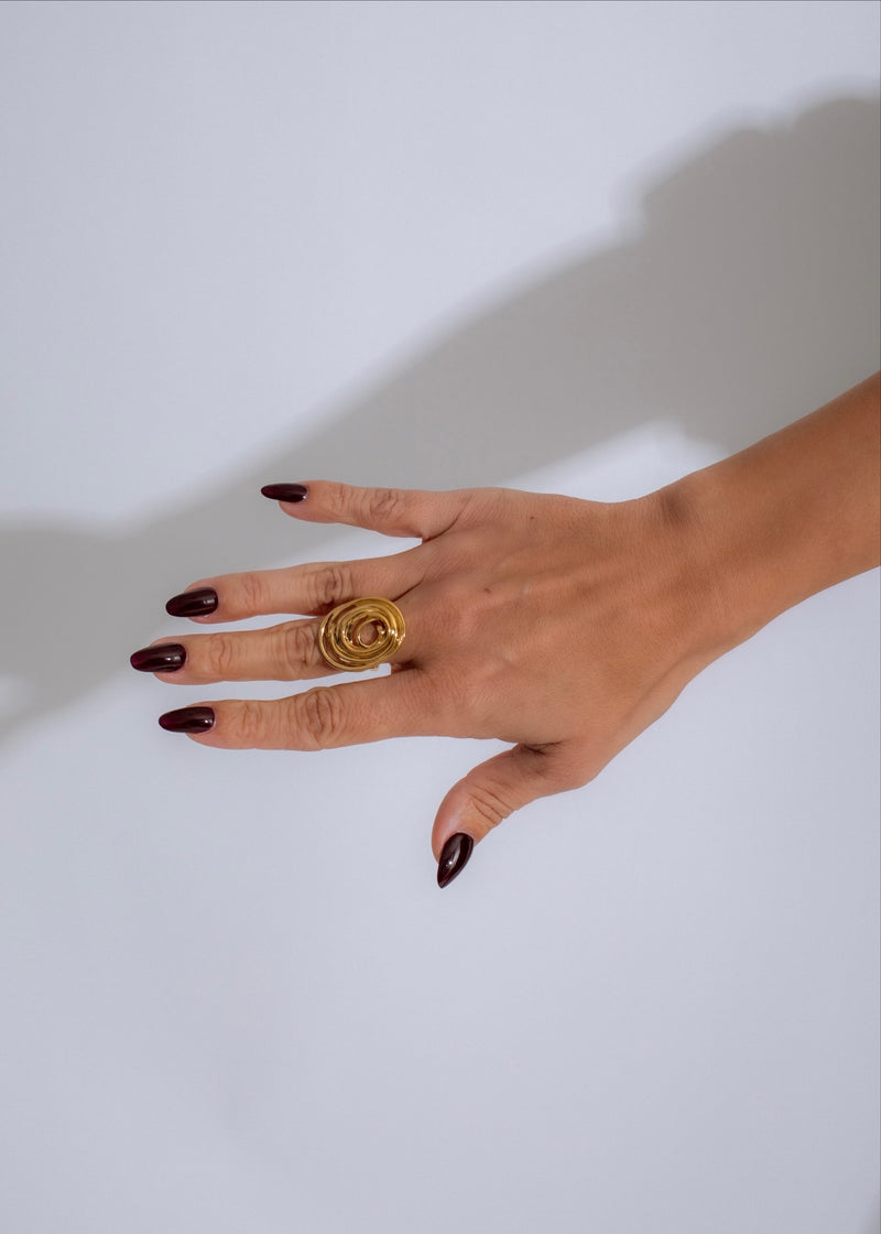 Close-up of elegant Orbit Twist Ring Gold in shimmering sunlight, showcasing its intricate design and luxurious shine