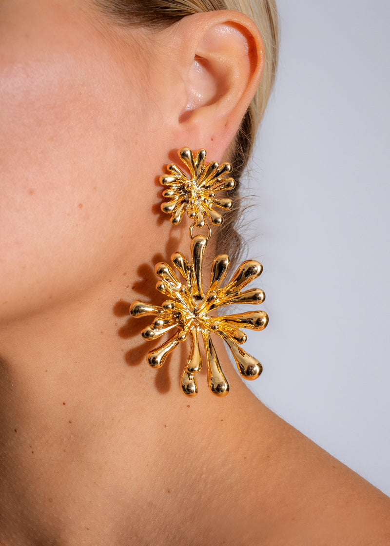 A close-up image of a pair of Solar Flare Earring Gold, featuring a shimmering gold design with intricate solar-inspired details