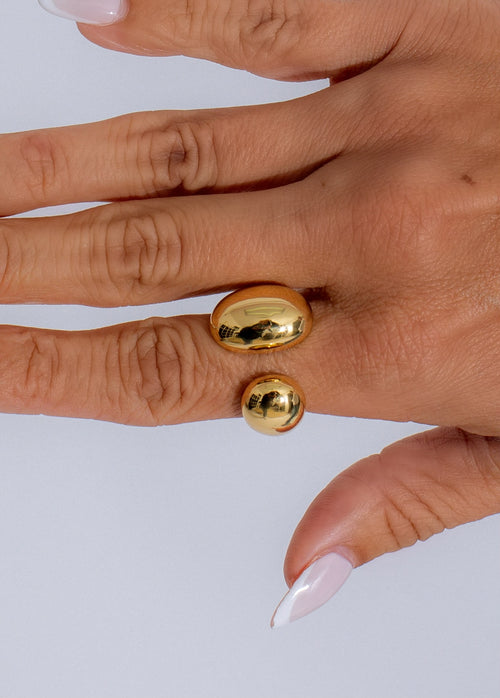 Shiny oval metallic gold ring with a polished finish and intricate design