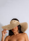 Close-up of a woman wearing a stylish nude hat with a wide brim on a sunny beach in Malibu, California 