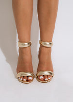 Shimmering gold high-heeled sandals with ankle strap, perfect for special occasions